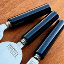 Três facas para queijos da marca Johnny Cooker com lâminas de aço inox polido (modelos lança, cutelo e espátula) e cabos cilíndricos em pedra natural Ágata polidos brilhantes.