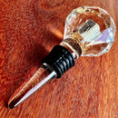 Stopper Cristal Gold Johnny Cooker para garrafas de vinho, com haste cônica , equipadas com anéis de vedação de silicone preto. Topos em material transparente facetado (nos formatos diamante e gota), revelando em seu interior um preenchimento denso de folhas douradas brilhantes.