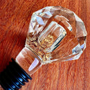 Stopper Cristal Gold Johnny Cooker para garrafas de vinho, com haste cônica , equipadas com anéis de vedação de silicone preto. Topos em material transparente facetado (nos formatos diamante e gota), revelando em seu interior um preenchimento denso de folhas douradas brilhantes.