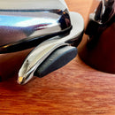 Stopper Hermético para Garrafas de Vinho Johnny Cooker em aço inoxidável prateado com mecanismo da alavanca de pressão, corpo em aço inox e base interna circular de silicone responsável pela vedação.